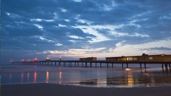 Plataforma de pesca de Tramandaí, Rio Grande do Sul, ao entardecer, sob céu nublado.
